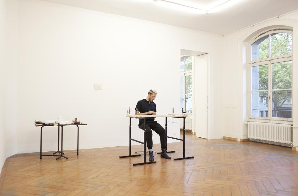 view of gallery room with artist and his working space in the middle of it