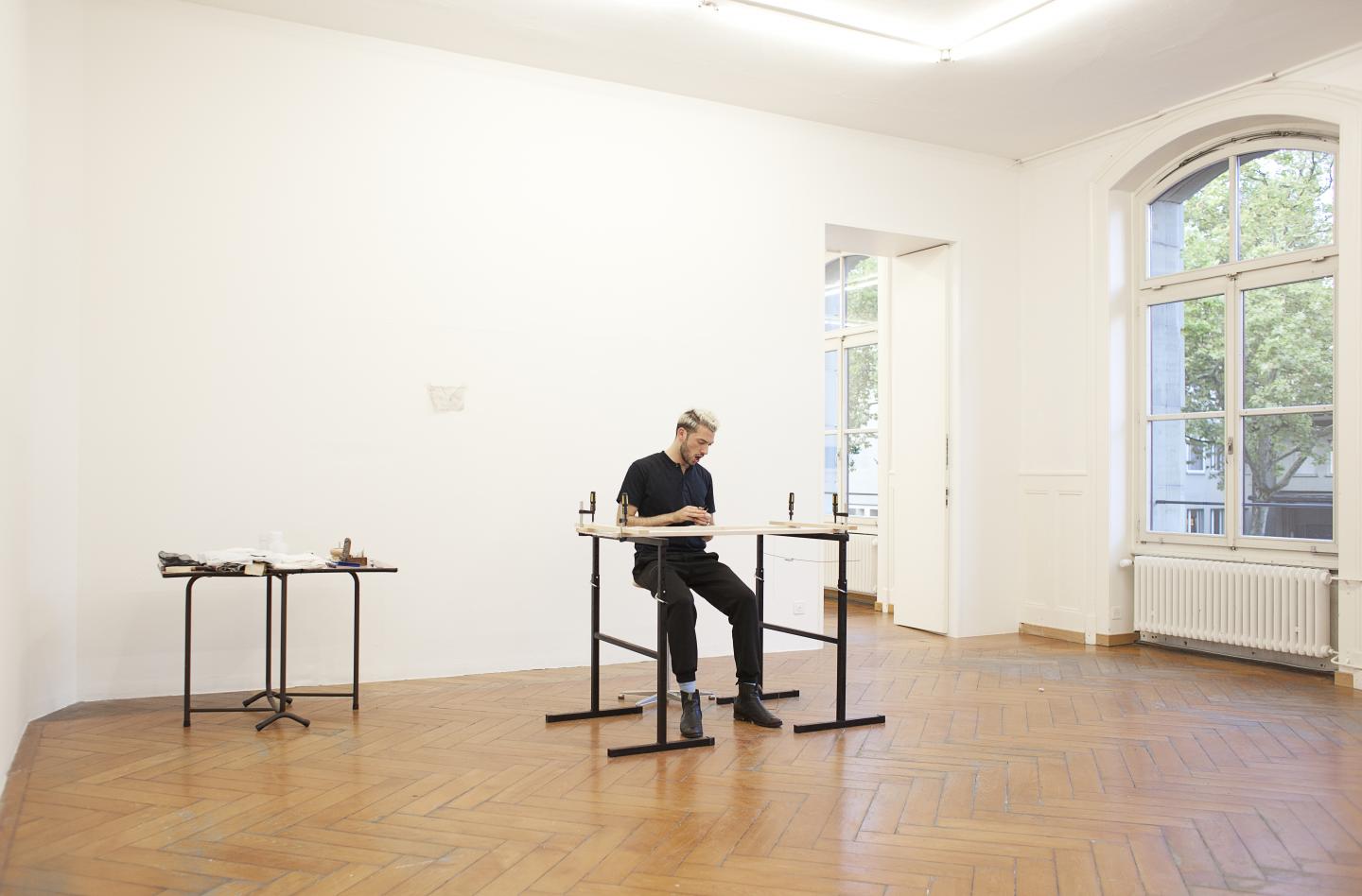 artist doing embroidery and singing in the middle gallery space