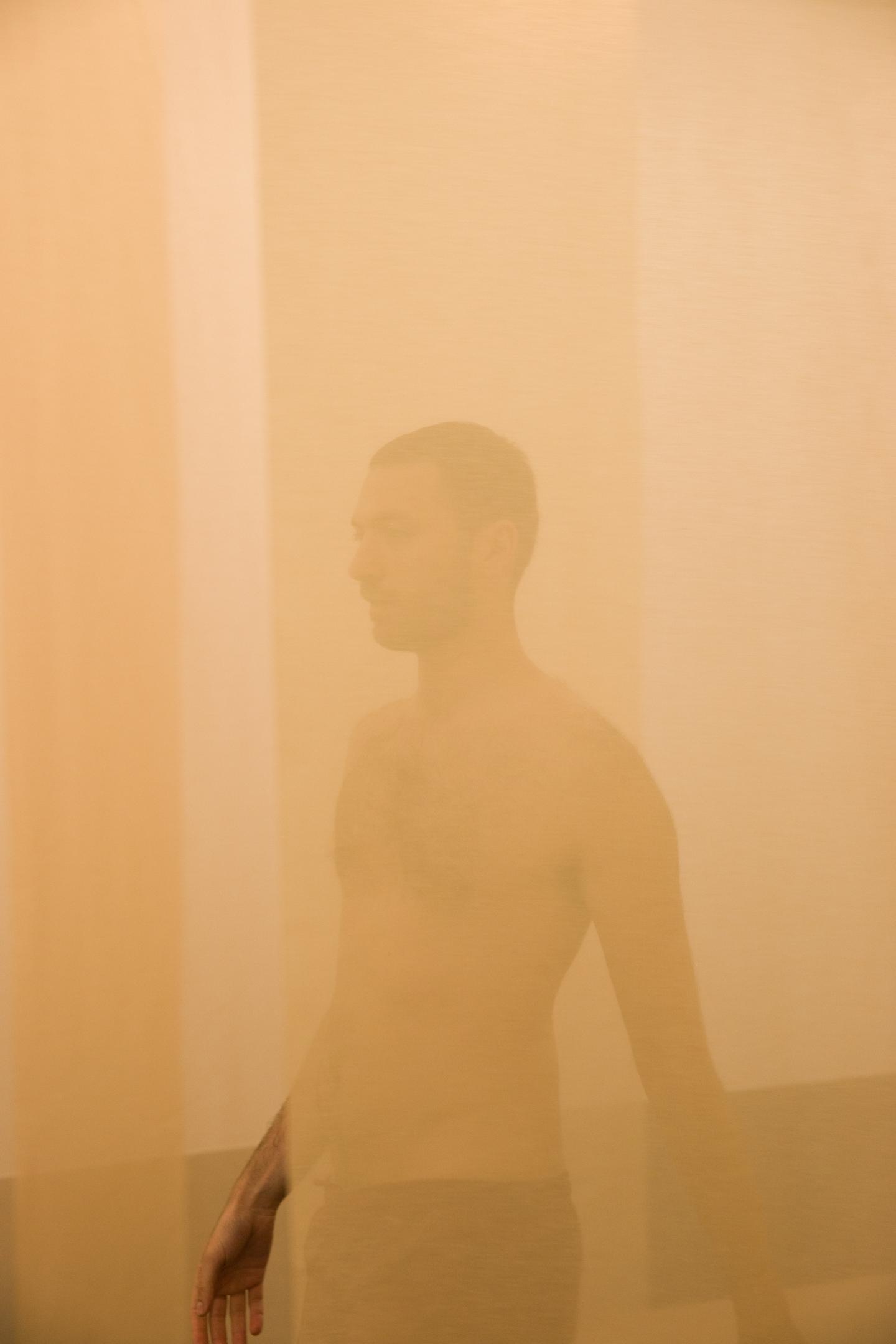artist walking between transparent curtains