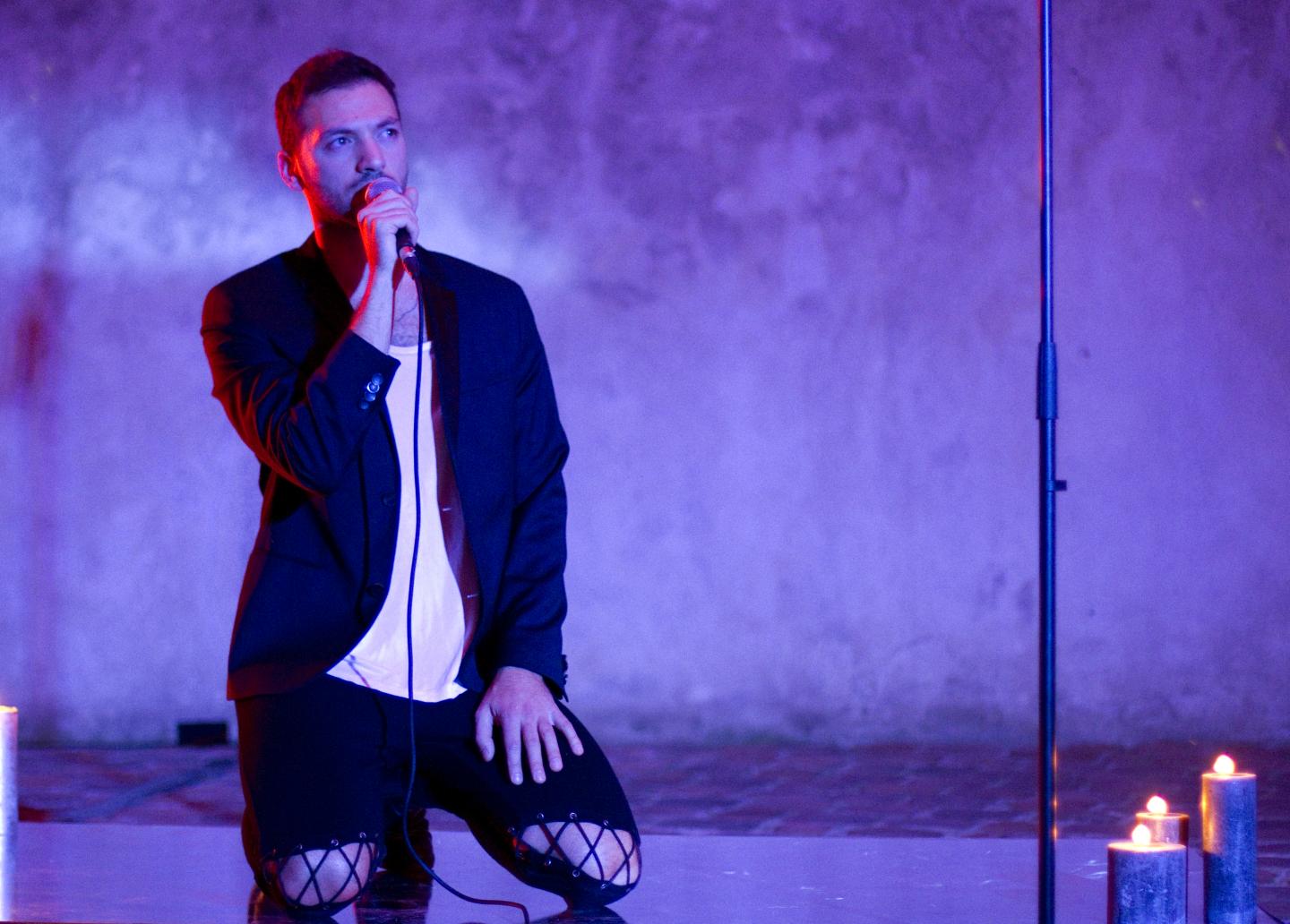 artist on knees singing into microphone
