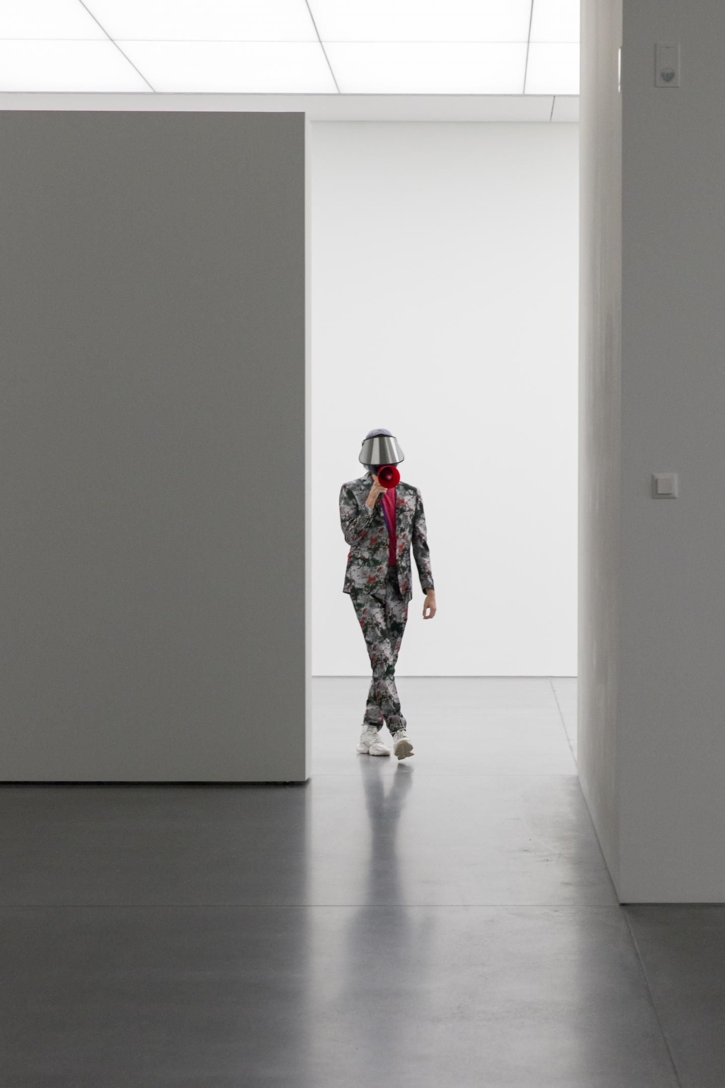 masked performer walking with red megaphone